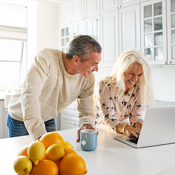 smiling couple at the kitchen island on their laptop reasonable rate of return money for retirement orlando fl medicare plan options